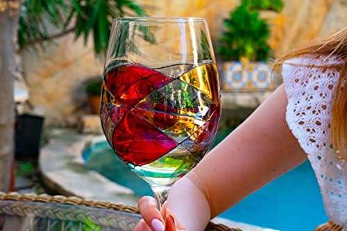 Colorful wine glass held by poolside.