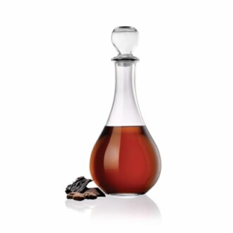 Elegant glass decanter with brown liquid and vanilla pods.