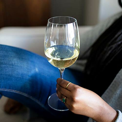 Person holding a glass of white wine.