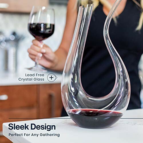 Elegant wine decanter with person holding a wine glass in the background.