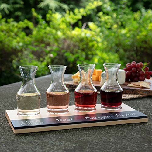 Outdoor wine flight with four glasses on a board, cheese and grapes in background.